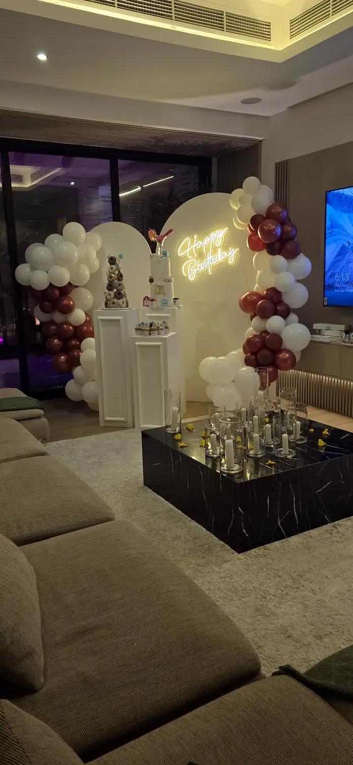 Burgundy and white balloons around an arch and display stands in a sitting room with sofas