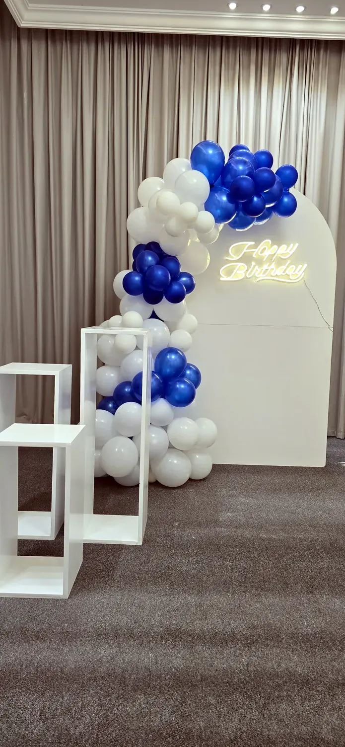 Blue and white balloons flowing over white display cubes beside long curtains